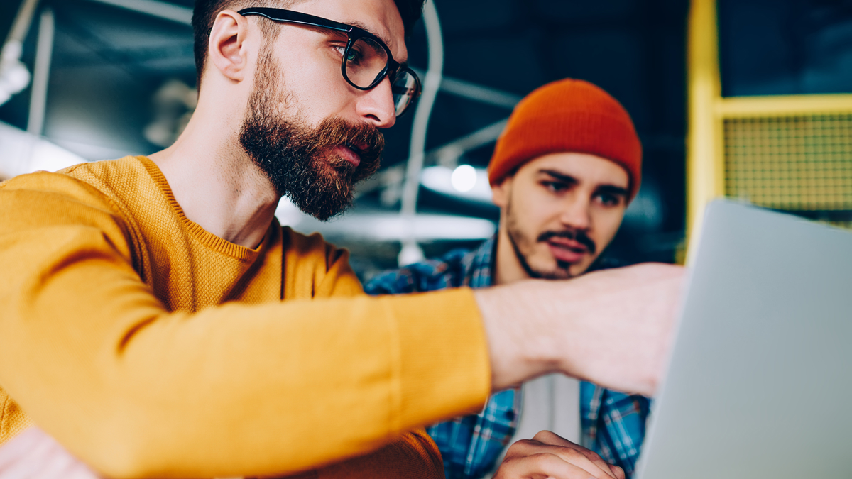 En man visar en annan man något på sin dator.