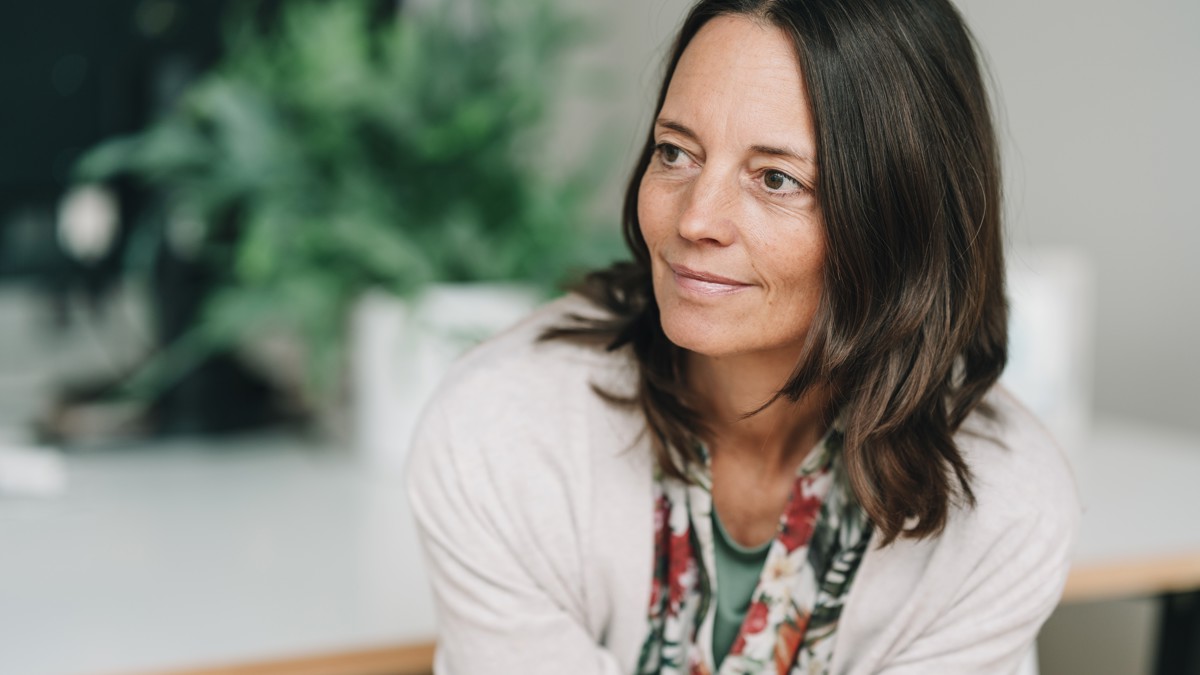 En medelålders mörkhårig kvinna tittat åt sidan.