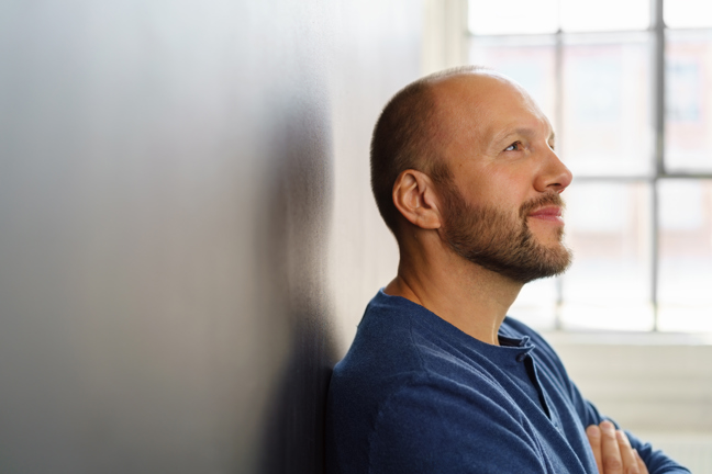 En man lutar sig mot en vägg och reflekterar.