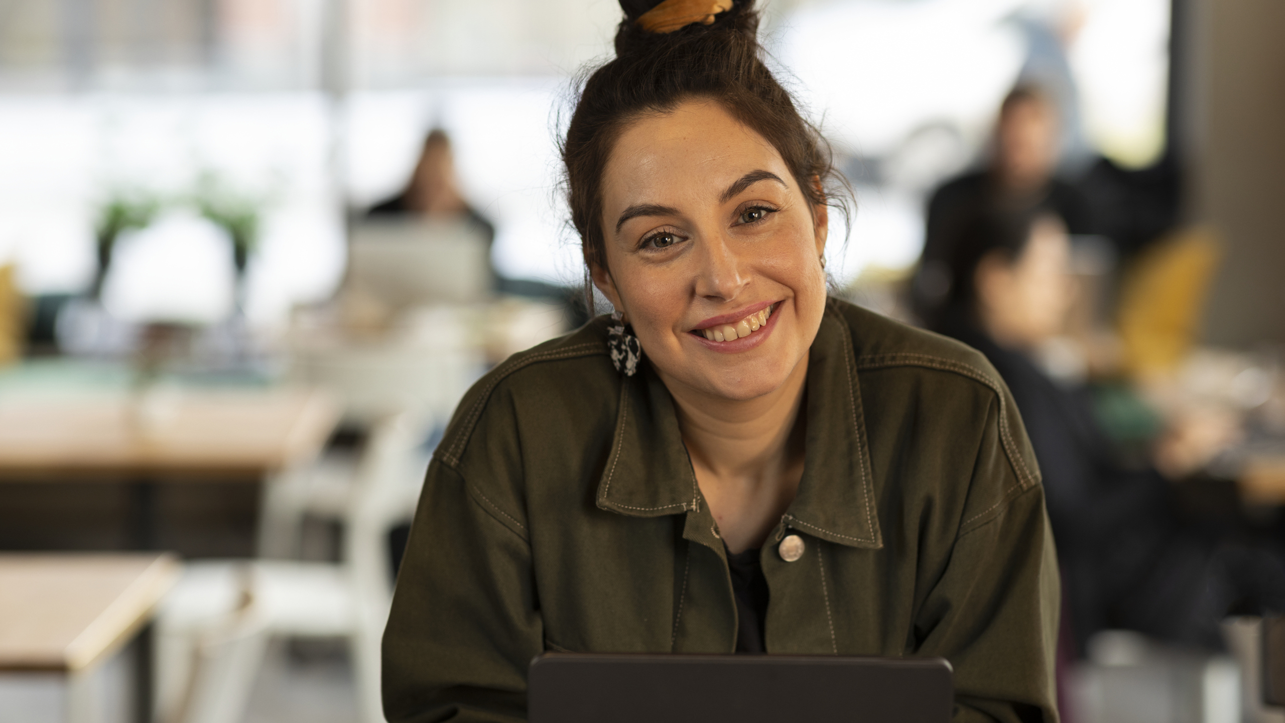 Glad kvinna med knut på huvudet tittar in i kameran
