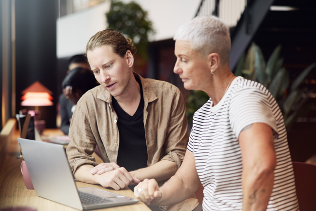 Yngre man och medelålders kvinna vid datorn.