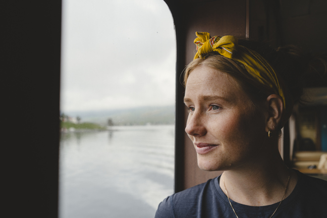 Ung kvinna tittar ut genom ett fönster.